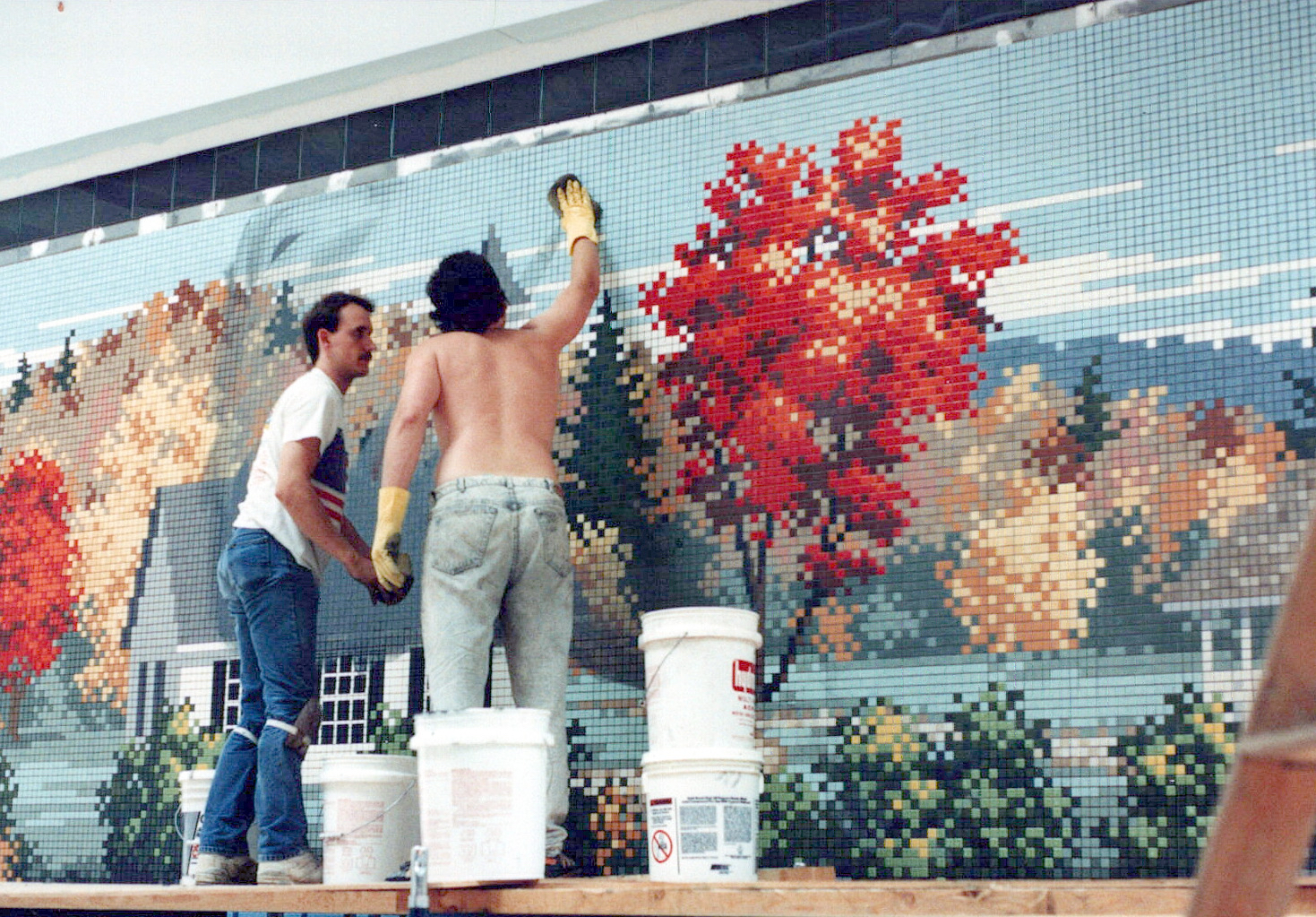 A photo of the staff at Capital Tile & Marble installing a mural of tile featuring fall leaves in New England